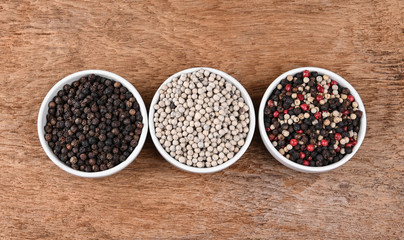 White pepper ; Black pepper ; Red pepper on wooden table, top view