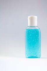 A bottle of hand sanitizer gel. Hand hygiene as coronavirus protection. Antivirus and antibacterial product. Blue liquid with white round granules. Copy space for text
