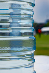 Clear cooler on a white plastic table on a football pitch ready for players to stop by during their break. Fresh water tank provided for everyone in a high school soccer tournament during summer time.