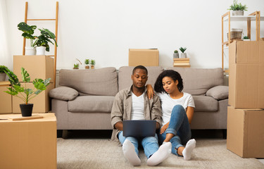 African american couple sitting on floor with laptop