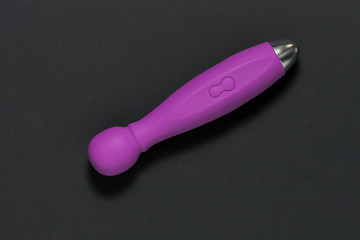 Erotic pleasure toy on a black background. Sex gadget and masturbation device. A purple rubber and...
