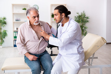 Obraz premium Old man visiting young male doctor cardiologist