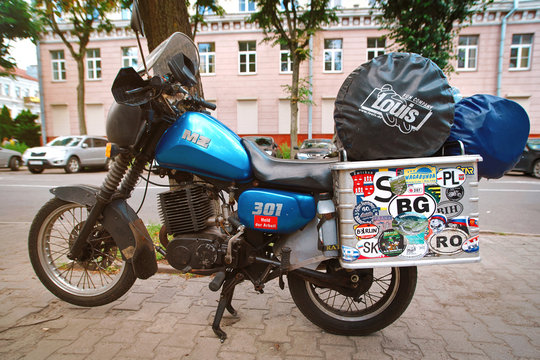 Minsk, Belarus. Jul 2019. Vintage MZ ETZ 301 - brand East German mortorcycle with metal suitcase covered with stickers from different countries. Motorcycle with travel baggage parked on the street