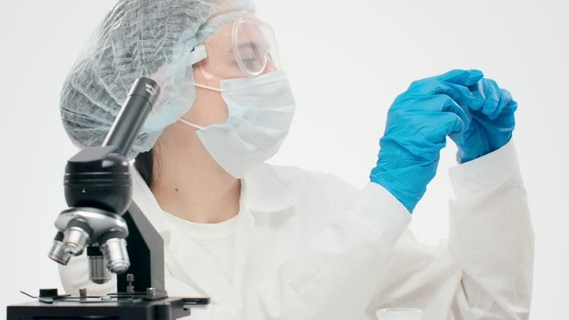 Close-up of a laboratory worker in medical equipment holds a gla
