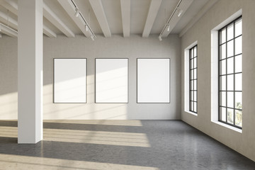 Three blank posters in sunlit gallery interior
