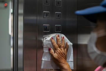 Close up of female hand using wet wipe to clean the door handle before touch and open the door.Antiseptic,disinfection ,cleanliness and healthcare, anti virus concept. anti Corona virus (COVID-19).