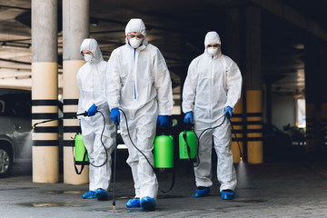 Fototapeta premium Workers in coronavirus suits cleaning streets with chemicals