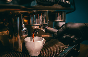 coffee machine is pourig coffee to white cup in bar