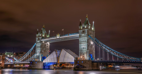 Tower Bridge, London, United Kingdom. Old bridge on the River Thames, lifting to allow a boat to pass underneath at night