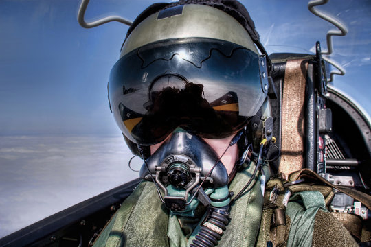 Royal Air Force ( RAF UK ) Pilot in the cockpit in an ejector seat wearing helmet, visor and oxygen mask flying high above the clouds Top Gun style fighter pilot black visor
