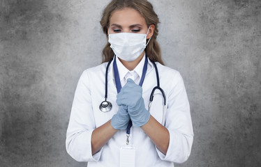 Medical staff preventive gear against coronavirus. Woman doctor in mask with closed eyes praying.