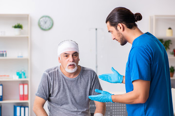 Fototapeta premium Young male doctor and old patient in first aid concept