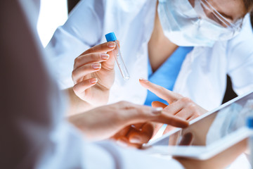 Coronavirus pandemic. Professional female scientist in protective eyeglasses researching tube in...