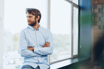 Portrait of a caucasian man in casual shirt standing near the window. Businessman portrait