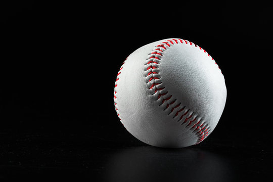 Baseball game equipment on dark black background close up
