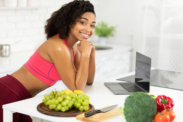 Black girl using laptop searching recipes looking at camera