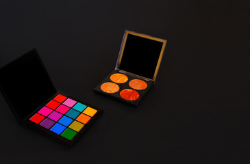 A palette with bright and multicolor shades and a highlighter palette on a black background. Copyspace