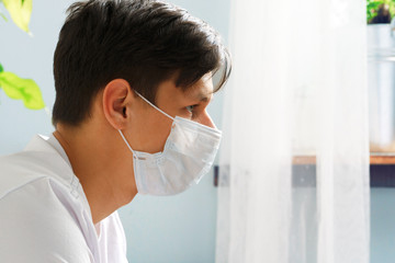 Caucasian man staying at home during Coronavirus / Covid-19 quarantine wearing medical mask