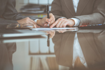 Two female accountants checking financial statement or counting by calculator income for tax form,...