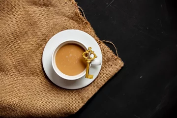 Foto auf Leinwand White cup of coffee and golden key on dark background © Masson