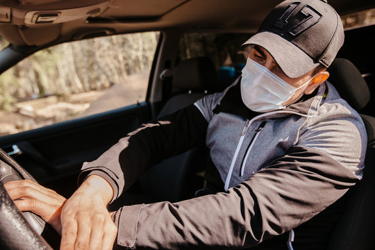 A man in a medical mask (respirator) gets out of a car during an epidemic