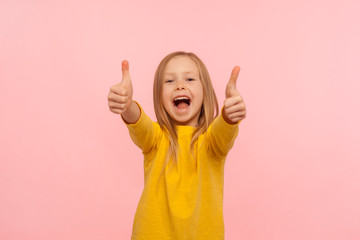 I like it, well done! Portrait of amazed happy excited little girl showing thumbs up gesture and...