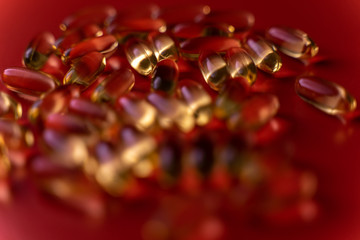translucent yellow capsules on a red saturated background. the topic of developing a vaccine for coronavirus COVID-19. contrasting alarming medical background with selective focus and blur.
