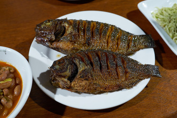 Two bbq fish, beans and salad for dinner on an open table.