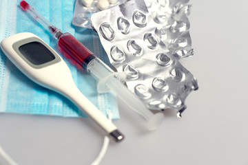syringe with red liquid, disposable mask, tablets in a blister, empty blisters for tablets, electronic thermometer