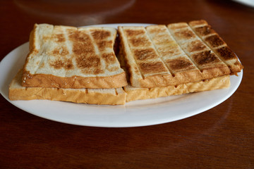 Breakfast сrispy fried toasts on a white plate on a wooden table.  
