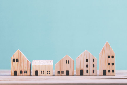 Building different wood house model on blue background , managing property investment concept