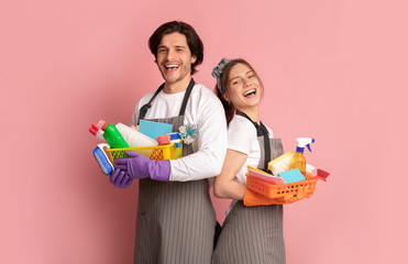 Team of janitors with cleaning supplies on pink background