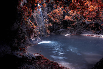 Fototapeta na wymiar The Blue Lagoon on a tropical island paradise. Blue lake and small waterfall. Bright exotic nature with fresh water stream. Dark trees and white waterfall.