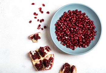 Grains of peeled pomegranate lie in a plate on a white background. Top view. Close-up. Copy space for text.