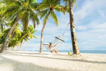 Photo sur Plexiglas Zanzibar Woman in hat sitting in hammock on the beach. Travel and vacation concept.