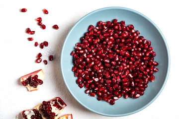 Grains of tasty, bright red peeled pomegranate lie in a plate on a white background. Top view. Close-up.