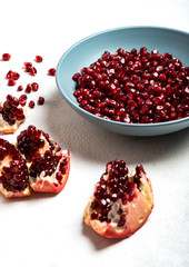 Grains of tasty, bright red peeled pomegranate lie in a plate on a white background. Close-up.