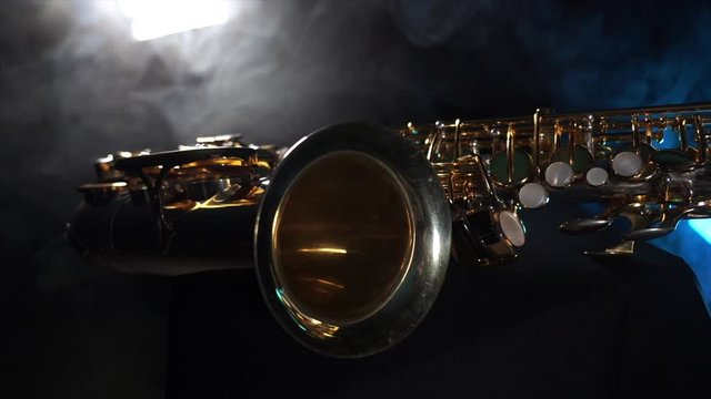 Golden shiny alto saxophone with blue smoke. Concept of grace and elegance