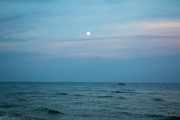 full moon in sunset evening sky over the ocean