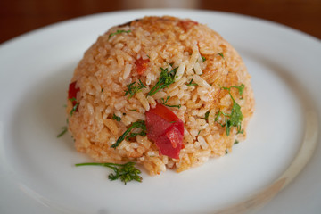 Spicy fried rice with vegetables on a white plate, dinner in a restaurant.   