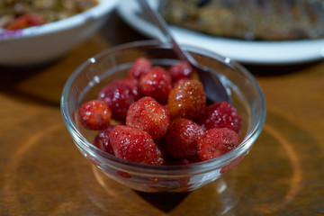 Strawberries in a glass plate on the wooden table. 