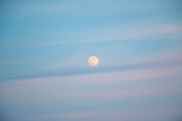 full moon in evening sky with clouds