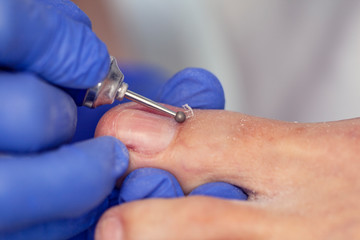 Obraz na płótnie Canvas Close-up nail care by a pedicure specialist in a beauty salon. Pedicure transparent cuticle professional scissors for pedicure.