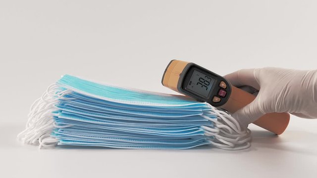 The nurse's hand places a contactless infrared thermometer on medical masks with a temperature of 38 degrees. High fever in Covid19 coronavirus patients.