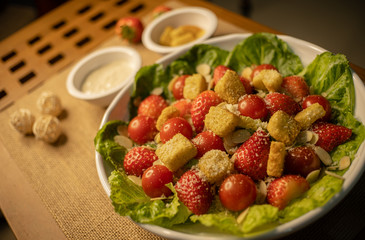 Caesar salad with strawberry on the wood table