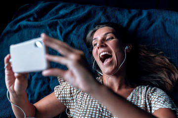A beautiful young female with headphones surprised during a videocall at time. Due to Coronavirus...