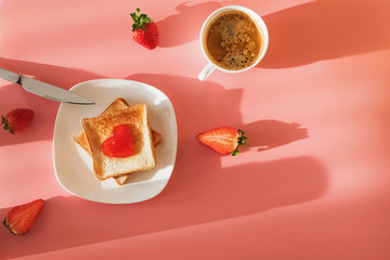 Toasted bread slices with jam in heart shape on it and cup of coffee in natural light