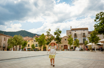 Fototapeta na wymiar Adorable toddler girl walking in medieval town of Besalu, province Girona, Spain. Family summer vacation. Catalonia, Spain
