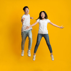 Fototapeta premium Carefree young asian couple posing over yellow background