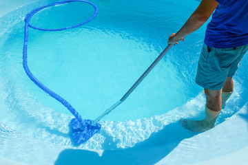 swimming pool cleaning. a man is cleaning the pool. service care